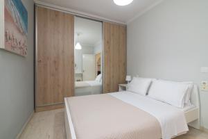 1 dormitorio con cama blanca y baño en Bilocale - Δίχωρο διαμέρισμα δίπλα στα Ψηλαλώνια en Patras