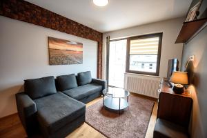 a living room with a couch and a table at Apartamenty Sun & Snow Zielony Zdrój in Krynica Zdrój