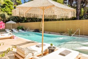 a pool with an umbrella and chairs and a swimming pool at Mandraki Village Boutique Hotel in Koukounaries