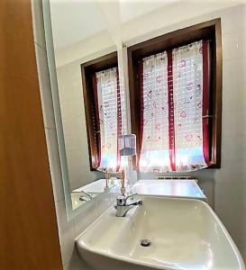 un bagno con lavandino, specchio e finestra di monolocale serena a Novara
