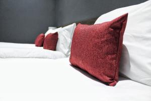 two red pillows sitting on top of a white bed at Devoncove Hotel Glasgow in Glasgow