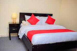 a bedroom with a large bed with red pillows at The Palm Residence in Kampala