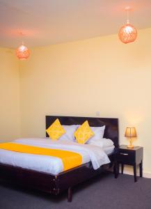 een slaapkamer met een bed met gele en witte kussens bij The Palm Residence in Kampala