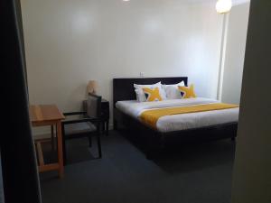 a bedroom with a bed with yellow pillows and a table at The Palm Residence in Kampala