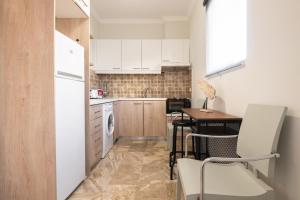 cocina con armarios blancos, mesa y sillas en Bilocale - Δίχωρο διαμέρισμα δίπλα στα Ψηλαλώνια en Patras