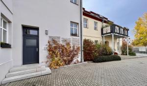 a white house with a black door on a street at Kungs Ferienwohnung in Cottbus
