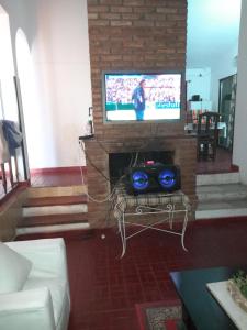 ein Wohnzimmer mit einem TV, einem Sofa und einem Tisch in der Unterkunft ESTANCIA VIEJA (CARLOS PAZ) in Estancia Vieja