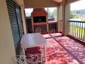 eine Veranda mit einem Tisch und Stühlen auf dem Balkon in der Unterkunft ESTANCIA VIEJA (CARLOS PAZ) in Estancia Vieja