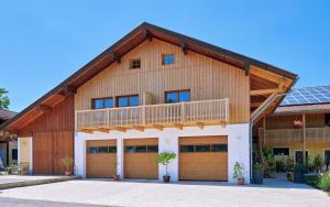 une maison avec deux portes de garage et un balcon dans l'établissement Ferienwohnung Tittmoning zwischen Salzburg und Burghausen, à Tittmoning