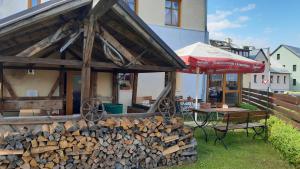a pile of fire wood next to a table and an umbrella at Resort Abertham - penzion Ellen in Abertamy