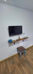a flat screen tv on a white wall with a bench at Casa IBIS in Mahmudia