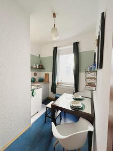 ein Esszimmer mit einem Tisch und einem weißen Stuhl in der Unterkunft Appartement Buntspecht in Erfurt
