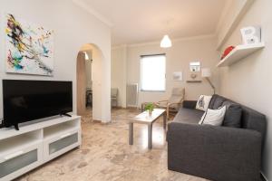 sala de estar con sofá y TV de pantalla plana en Bilocale - Δίχωρο διαμέρισμα δίπλα στα Ψηλαλώνια en Patras