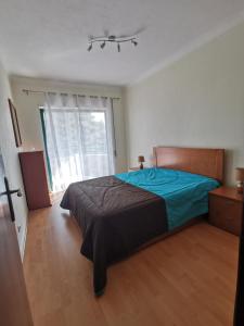 um quarto com uma cama e uma grande janela em Logement terrain de tennis/piscine 800m de la mer em Portimão