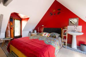 - une chambre rouge avec un lit et un lavabo dans l'établissement Le petit secret, à Saint-Aignan