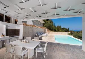 a patio with a white table and chairs and a swimming pool at Villa Anthos - Fresh modern villa, pool, close to the beach in Lefkada Town