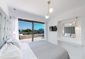 a white bedroom with a bed and a large window at Villa Anthos - Fresh modern villa, pool, close to the beach in Lefkada Town