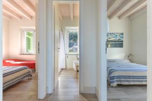 a white bedroom with two beds and a window at Il Quartiere apt Montecristo in Pomonte