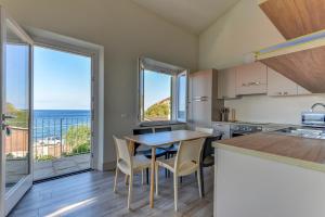 a kitchen with a table and chairs and a view of the ocean at Il Quartiere apt Montecristo in Pomonte