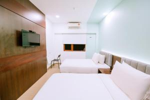 a hotel room with two beds and a flat screen tv at The Concept Hotel Langkawi in Kuah