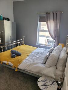 a bedroom with a bed with a yellow blanket and a window at Elegance apartments in West Cornforth