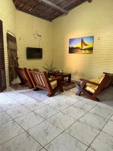 a patio with two wooden chairs and a television at Casa de Férias no Porto das Dunas in Aquiraz