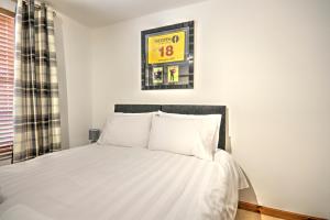 a bedroom with a bed with white sheets at 5 Argyle Place in Dornoch