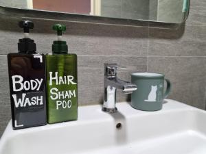 a bathroom sink with two bottles of soap and a cup at Pavilion 2 Revo l Rooftop Swimming Pool LS15 in Kuala Lumpur