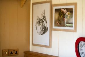 two framed pictures on a wall with a clock at Harrys Hideout - Shepherd's Huts at Harrys Cottages in Pen y Clawdd