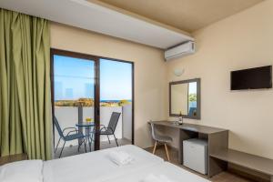 a hotel room with a bed and a desk and a balcony at Afandou Blu in Afantou