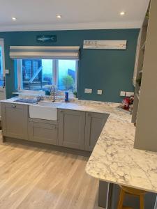 a large kitchen with a sink and a window at Wogan Cottage in Saundersfoot