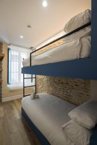 2 Etagenbetten in einem Zimmer mit Ziegelwand in der Unterkunft Wello Apartments Sevilla in Sevilla