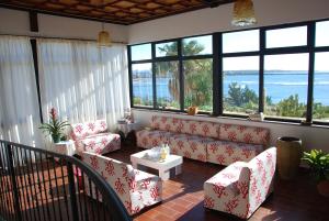 a living room with a couch and chairs and windows at Villarolu in Portoscuso