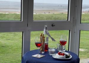 a table with two glasses of wine and a bird on a window at Haus Horizont Fewo Nr. 4 in Cuxhaven