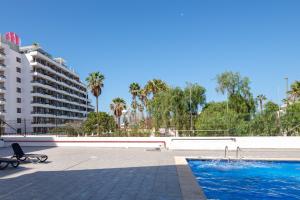 a swimming pool next to a building with palm trees at Casa Sami in Playa de las Americas