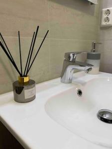 a bathroom sink with a vase with sticks in it at Moderne leilighet midt i sentrum av Fredrikstad in Fredrikstad