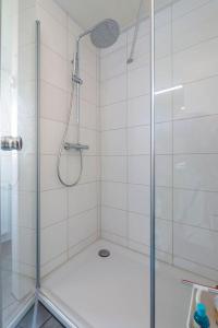 La salle de bains est pourvue d'une douche avec une porte en verre. dans l'établissement Luxe cottage met fietsen, airco & infrarood cabine, à Knokke-Heist