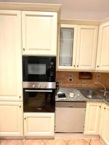 a kitchen with white cabinets and a black microwave at Colosseum Charming Stay in Rome +10 photos