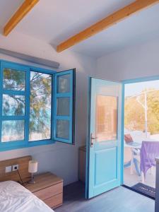 a bedroom with a blue door and a table at Paradise on Kantouni Beach-20m from Boutique Hotel in Kalymnos