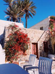 a table and chairs in front of a building with palm trees at Paradise on Kantouni Beach-20m from Boutique Hotel in Kalymnos