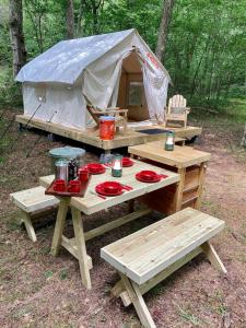 a picnic table with a tent in the woods at Tentrr Signature Site - Wander in Scottsville