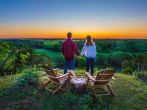 a man and a woman holding hands while standing next to chairs at Tentrr Signature Site - Beautiful Campsite near the Brazos River in Bellmead