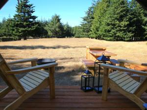 a deck with two chairs and a grill and a field at Tentrr - Cranberry Overlook at Black Moon Farms in Langlois