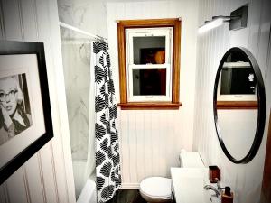a bathroom with a toilet and a window and a mirror at Charming Home Away from Home in Thunder Bay