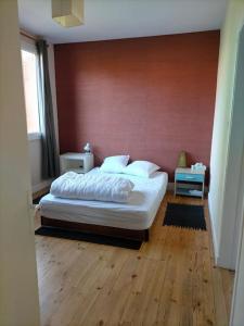 sypialnia z białym łóżkiem i czerwoną ścianą w obiekcie Petite maison très paisible avec jardin à Cournon - Puy de Dôme ! w mieście Le Cendre