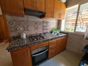 a kitchen with wooden cabinets and a stove top oven at Chez Najib et Ziad in Temara