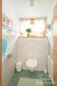 La salle de bains blanche est pourvue de toilettes et d'une fenêtre. dans l'établissement Panorama Appartement, à Ramsau am Dachstein