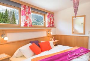 a bedroom with a bed and two windows at Panorama Appartement in Ramsau am Dachstein