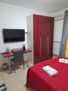 een slaapkamer met een rood bed, een bureau en een televisie bij jolly casa 2 in Cosenza