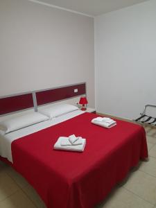a bedroom with a red bed with two towels on it at jolly casa 2 in Cosenza